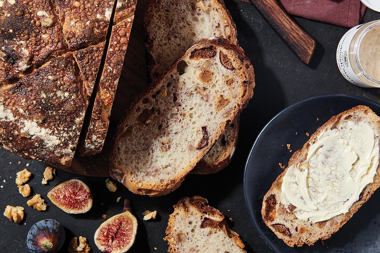 Close-up shot of a slice of sourdough bread with fig jam and walnuts, showing the texture and ingredients.
