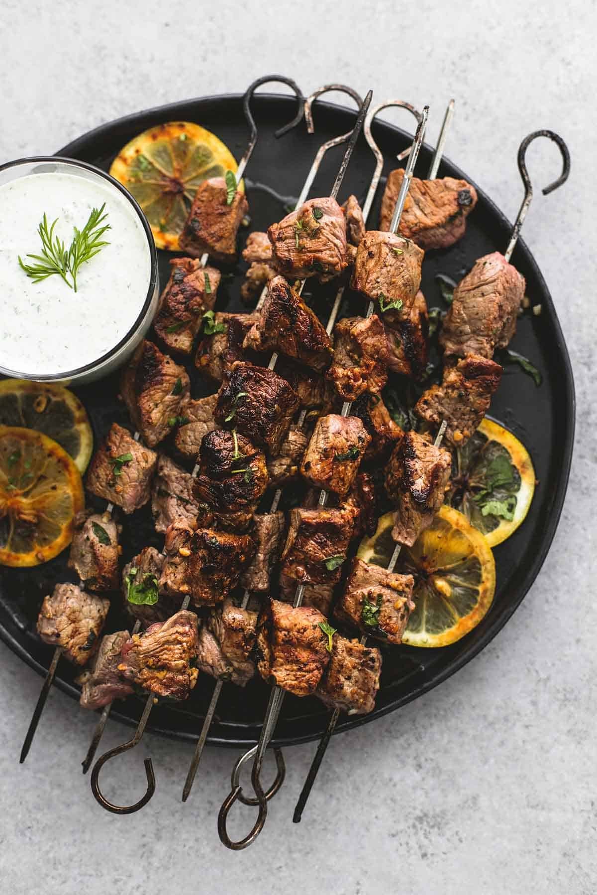 Mediterranean beef skewers with tzatziki sauce on a plate