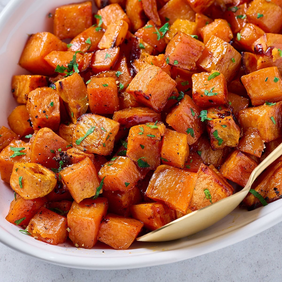 Close-up shot of roasted sweet potatoes glistening with maple syrup