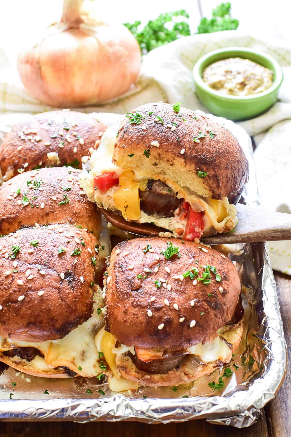 Sausage sliders with melted cheese being served on a wooden board