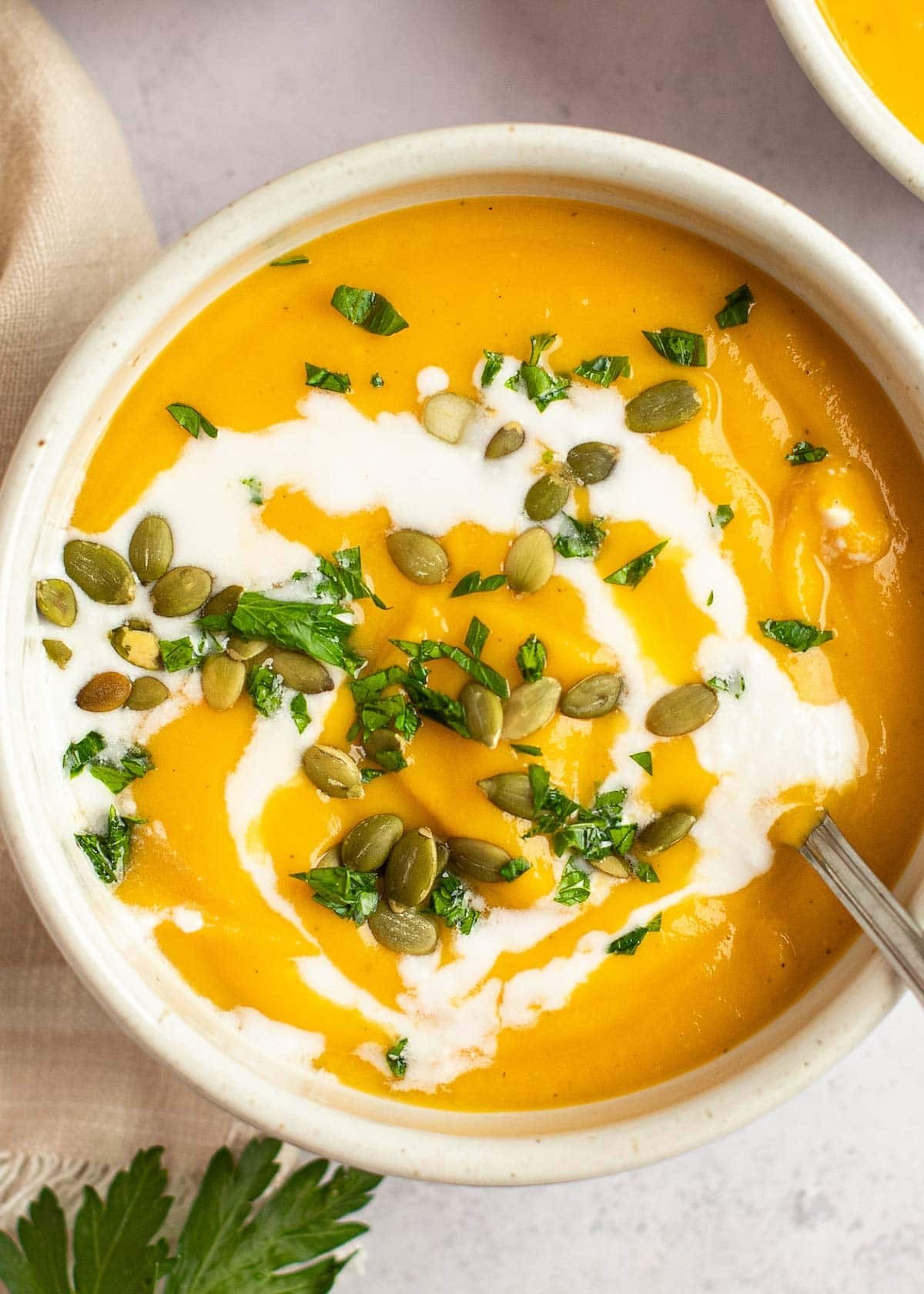 A rustic bowl of creamy sauerkraut and butternut squash soup, garnished with fresh herbs