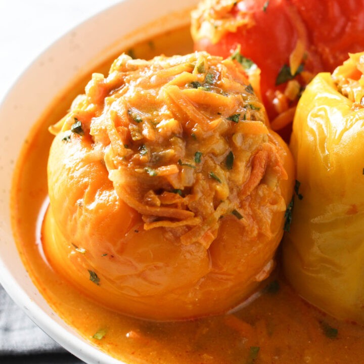 Close-up shot of vibrant stuffed bell peppers with a hearty brown rice filling, garnished with fresh herbs