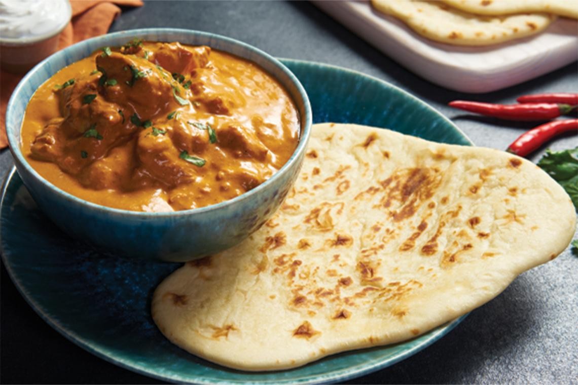homemade butter chicken being served with naan bread