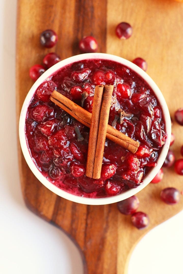 Homemade cranberry sauce with cinnamon sticks and orange slices in a rustic bowl