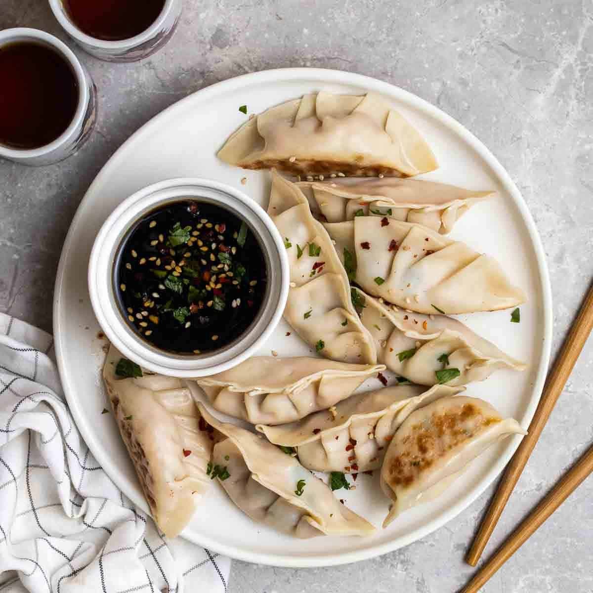 Close-up shot of steaming, delicate tofu and edamame dumplings arranged on a plate, garnished with fresh herbs and a drizzle of ponzu sauce