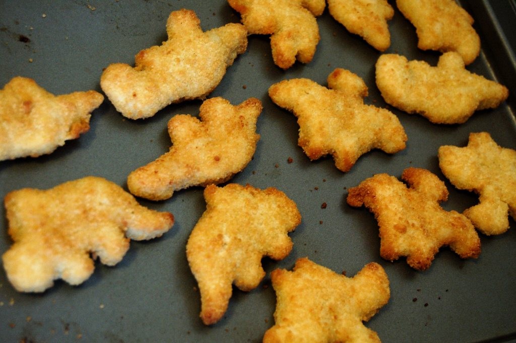 Close-up shot of crispy dino-shaped chicken nuggets on a baking sheet