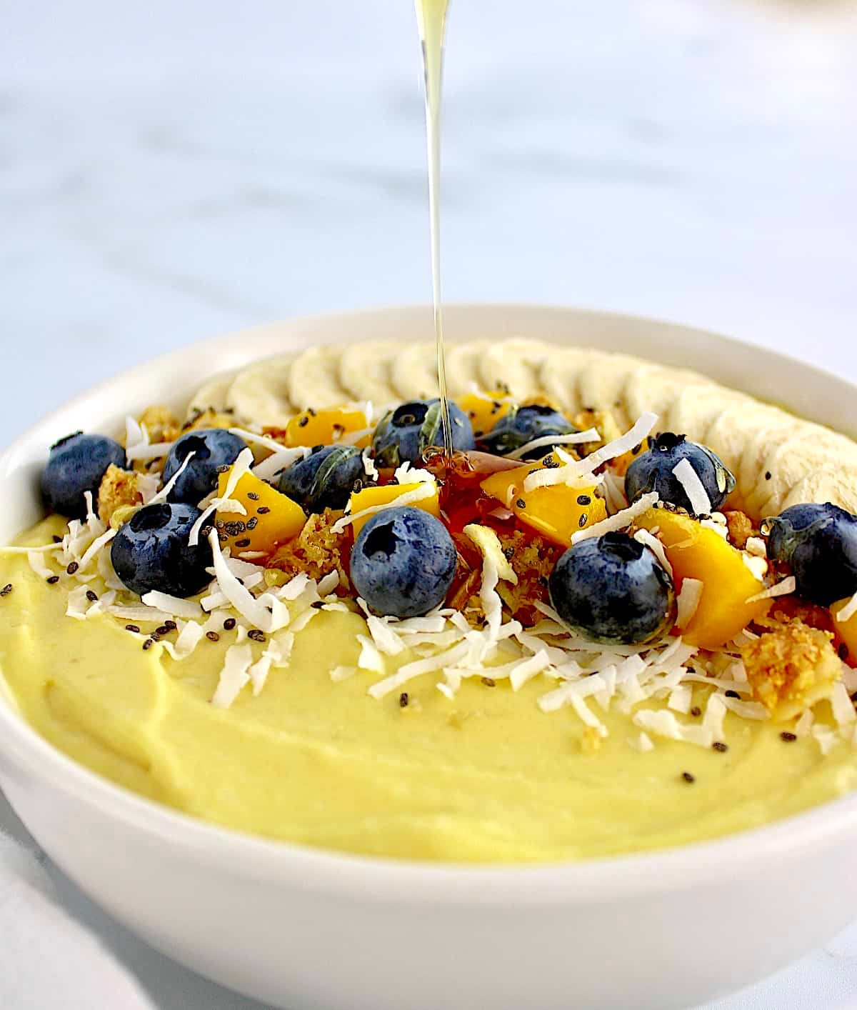 A bowl of creamy coconut yogurt topped with fresh mango and a sprinkle of nutmeg