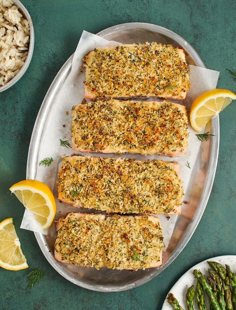 beautifully baked salmon fillet with a golden herb crust, lemon wedges, and fresh dill on a serving plate