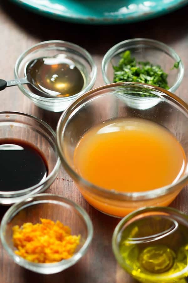 Close-up shot of a vibrant clementine and honey salad dressing in a glass bowl, garnished with fresh clementine segments