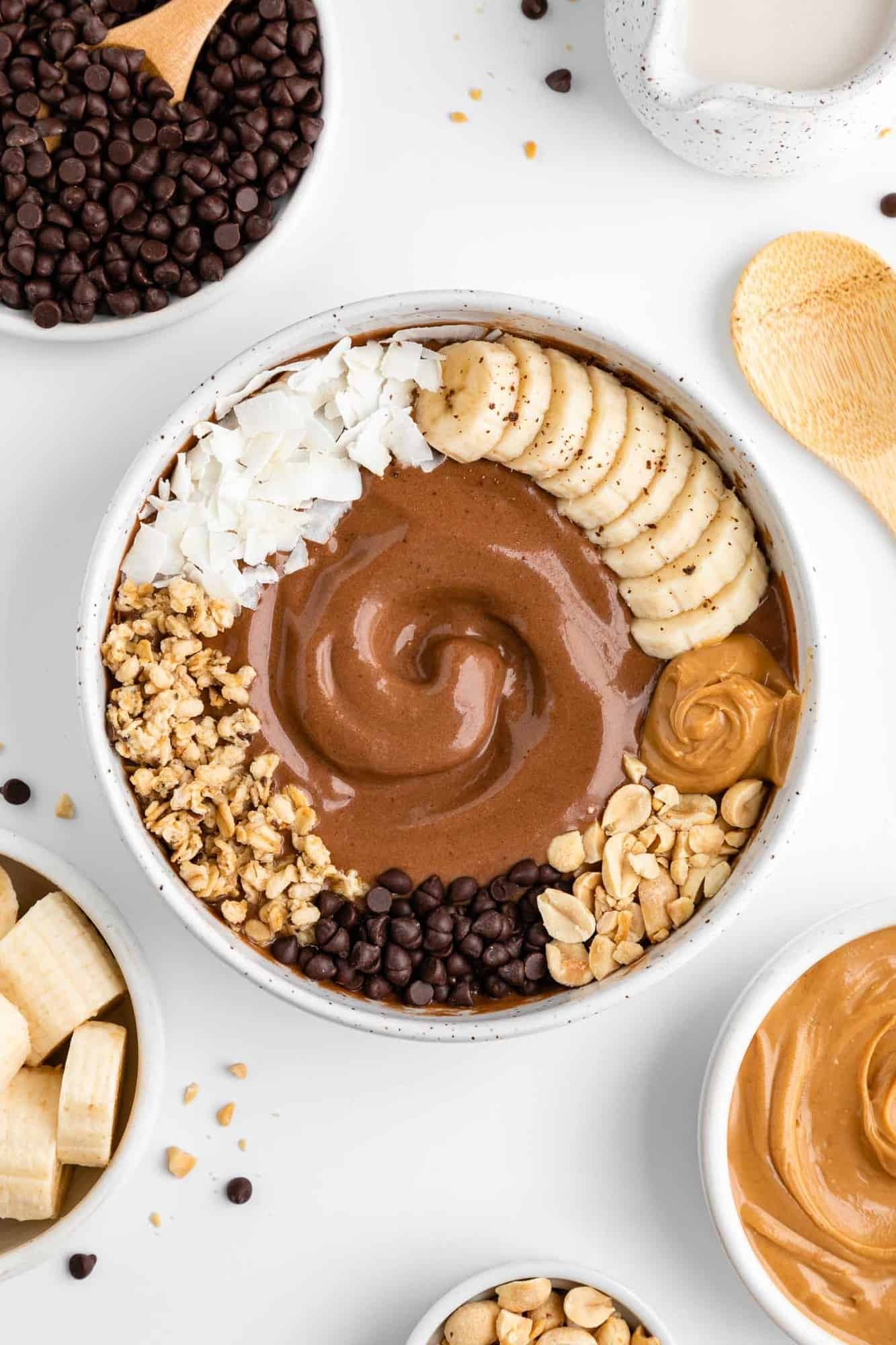 A vibrant and healthy grain bowl topped with peanut butter, chocolate ganache, and various toppings.