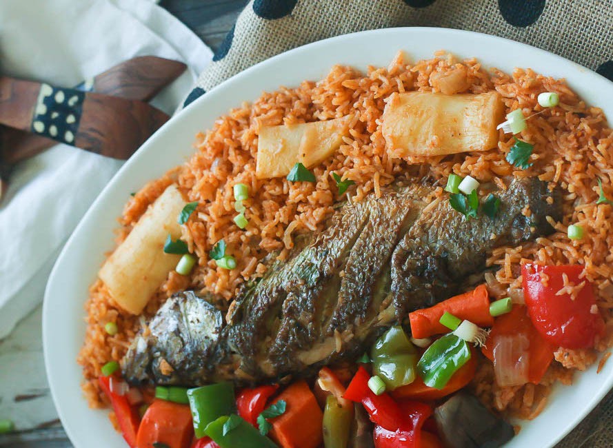 A steaming bowl of Guinea Rice with Meat, garnished with fresh parsley