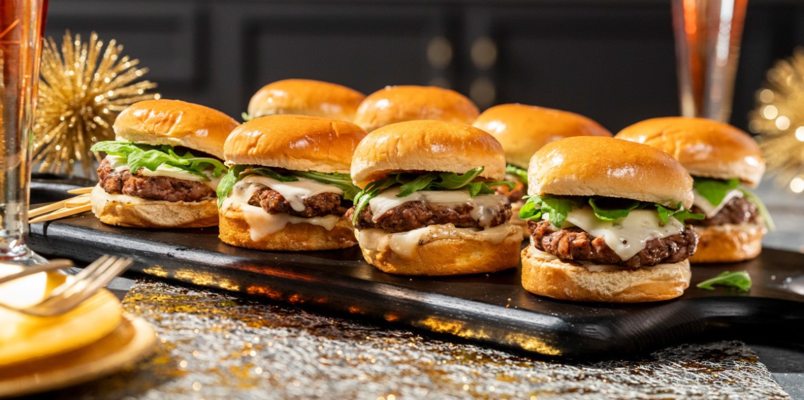 Close-up shot of Wagyu beef sliders with truffle aioli, garnished with fresh herbs