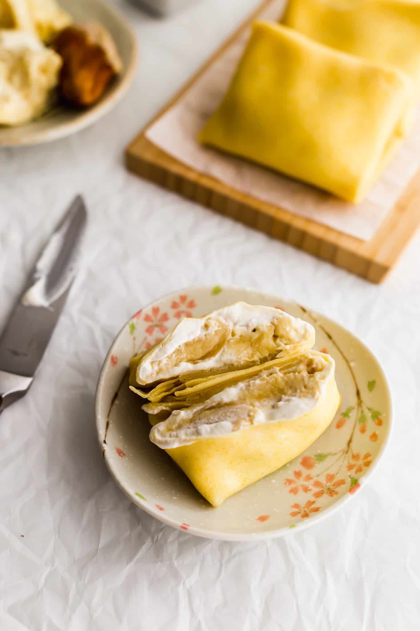stack of golden brown durian pancakes topped with whipped cream and durian pieces