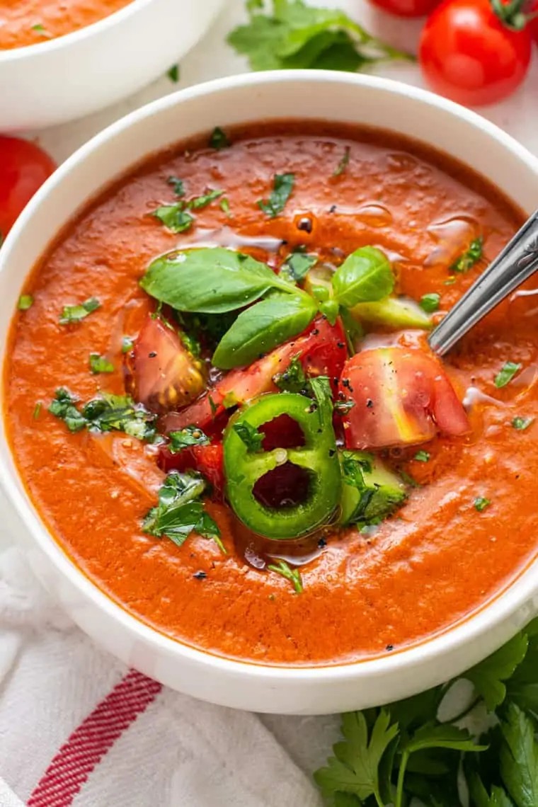 close up of a vibrant red spicy gazpacho soup with jalapeño and lime garnish