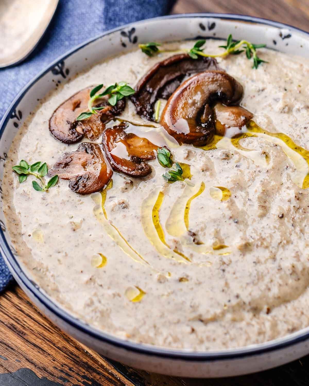 A rustic bowl of creamy mushroom soup garnished with fresh thyme sprigs