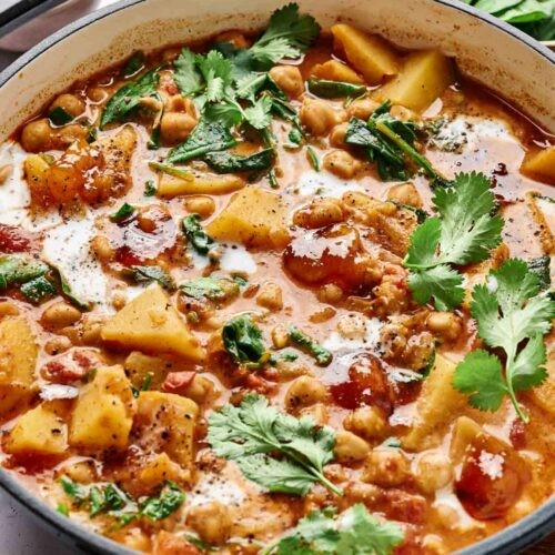 A vibrant and flavorful chickpea and potato curry in a rustic bowl, garnished with fresh cilantro