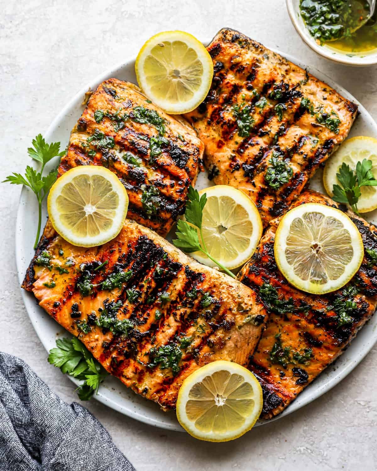 honey glazed grilled salmon on a platter with lemon wedges and herbs
