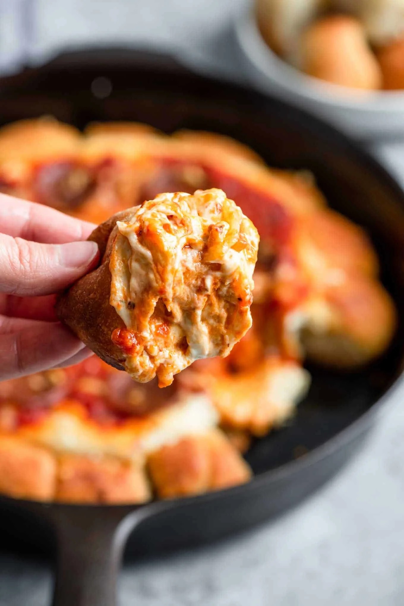 Close-up shot of mini pizzas in a cast iron skillet, cheese bubbling and golden brown