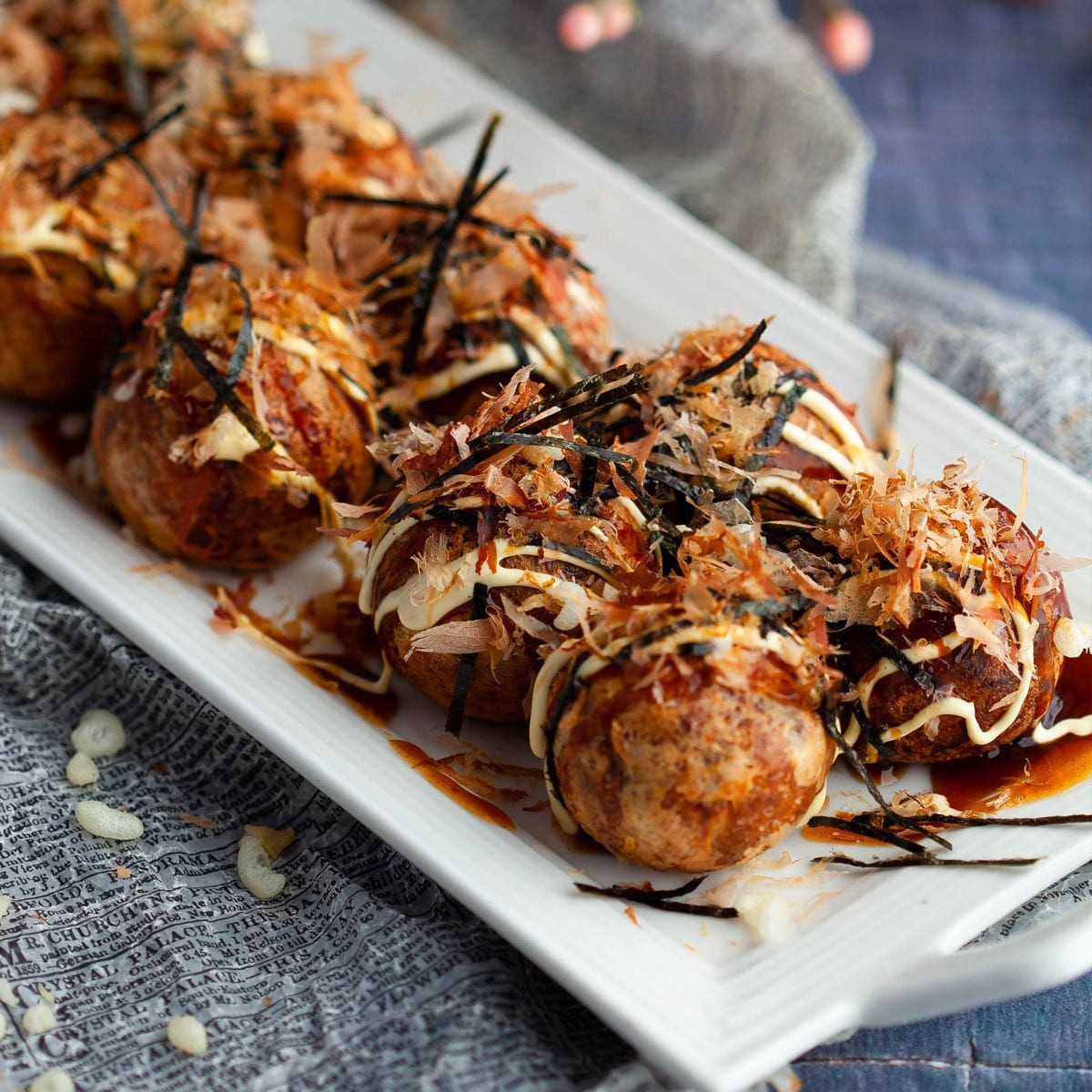 close up shot of golden brown takoyaki balls drizzled with sauce and toppings