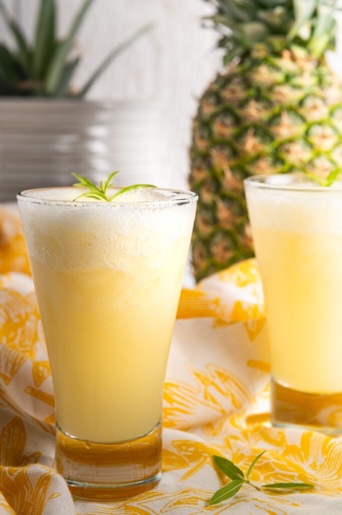 Refreshing glass of Pineapple Ginger Zing Lemonade with ice and pineapple wedges