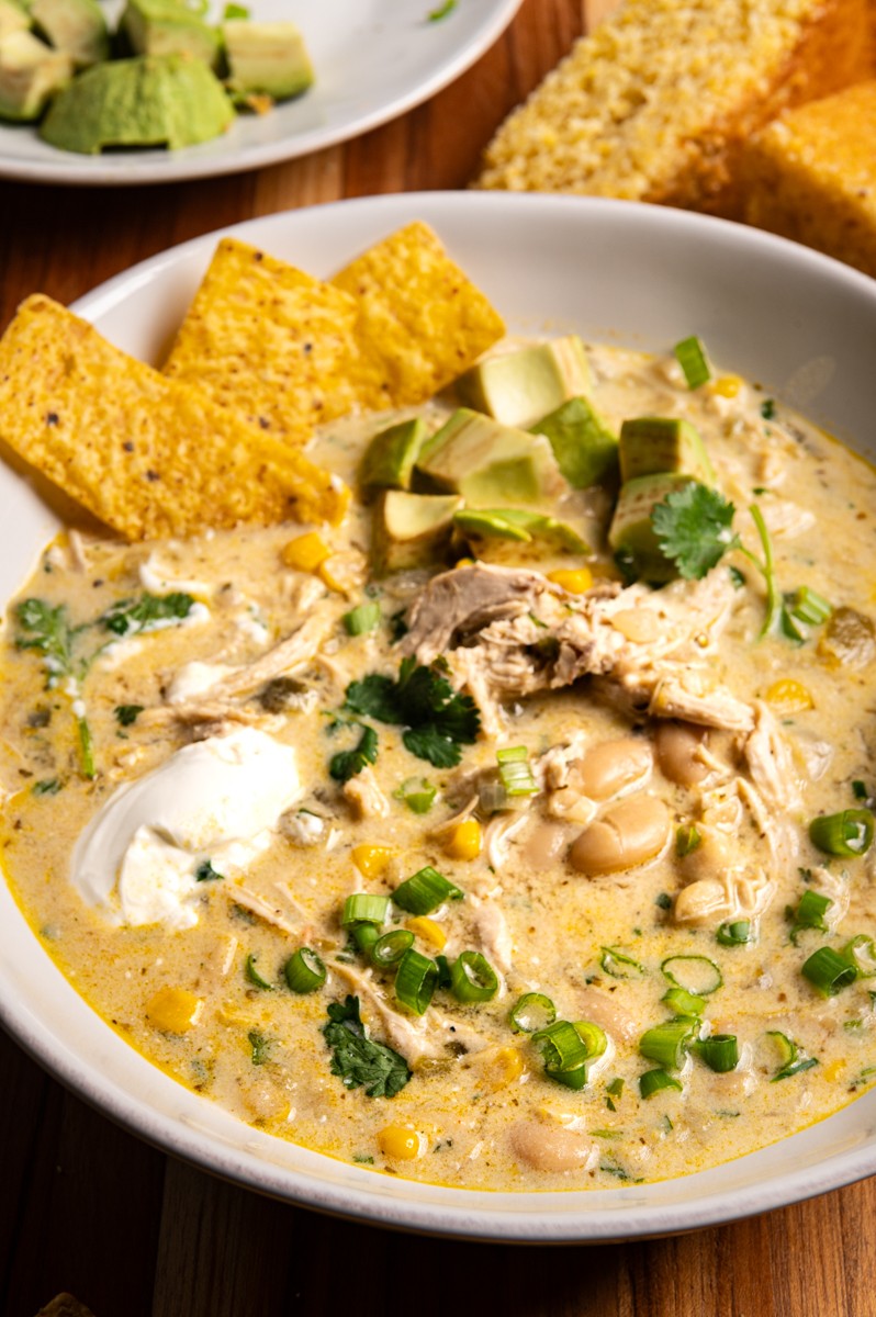 Rustic bowl of zesty white chicken chili with a spoonful of sour cream and cilantro garnish, cozy setting