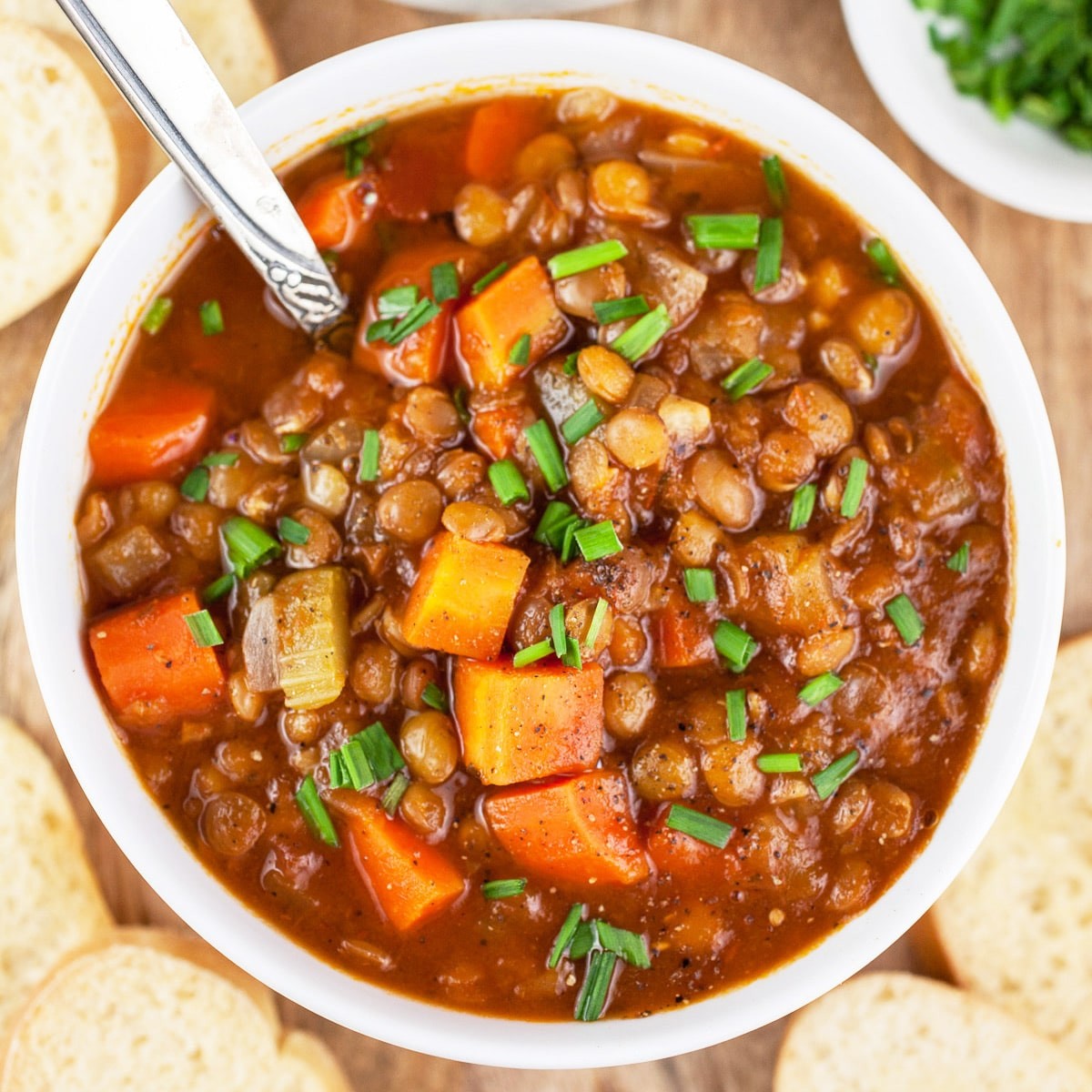 A rustic bowl of hearty lentil soup with apples and cider, garnished with fresh herbs