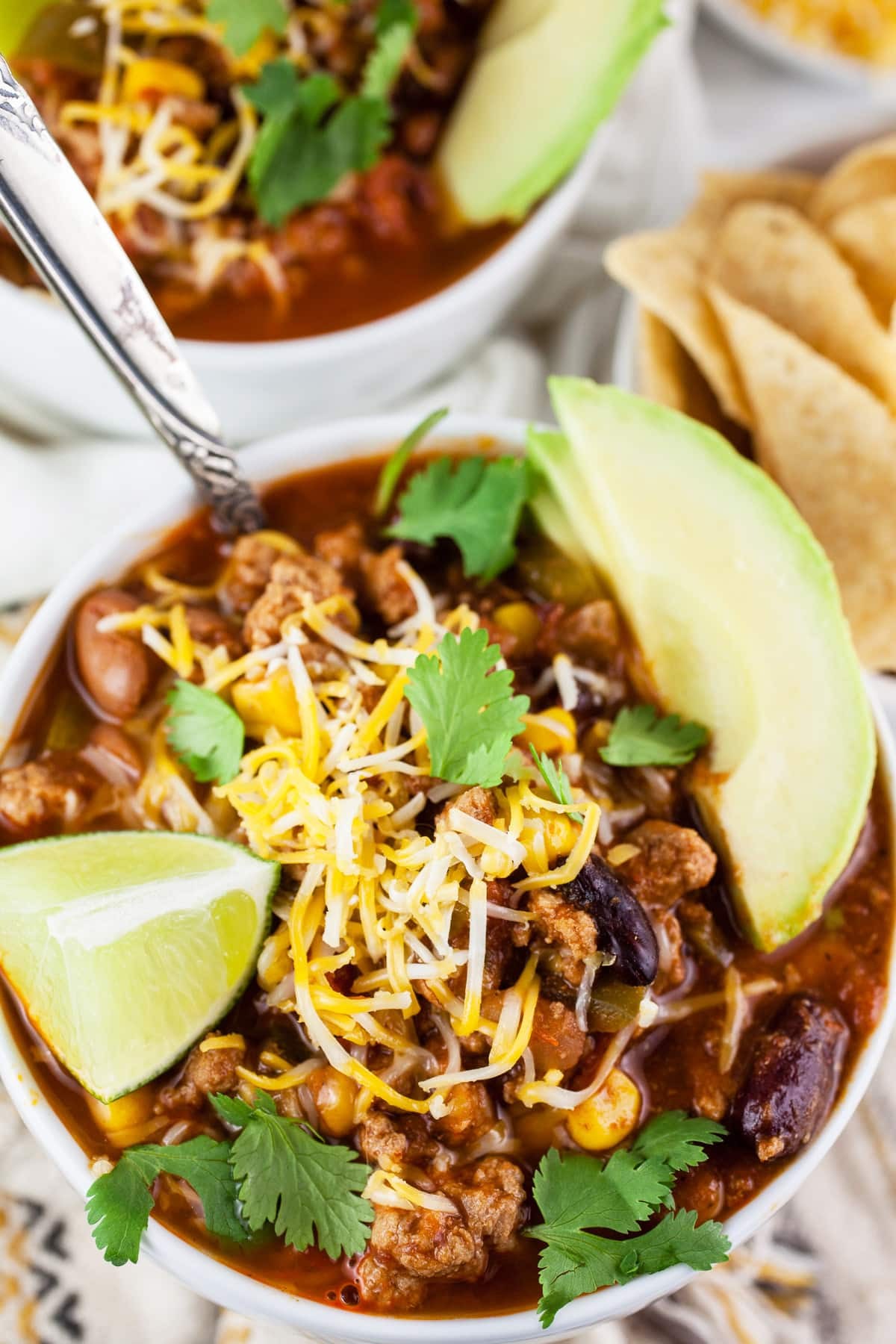 Slow cooker filled with spicy turkey chili garnished with cilantro and lime wedges