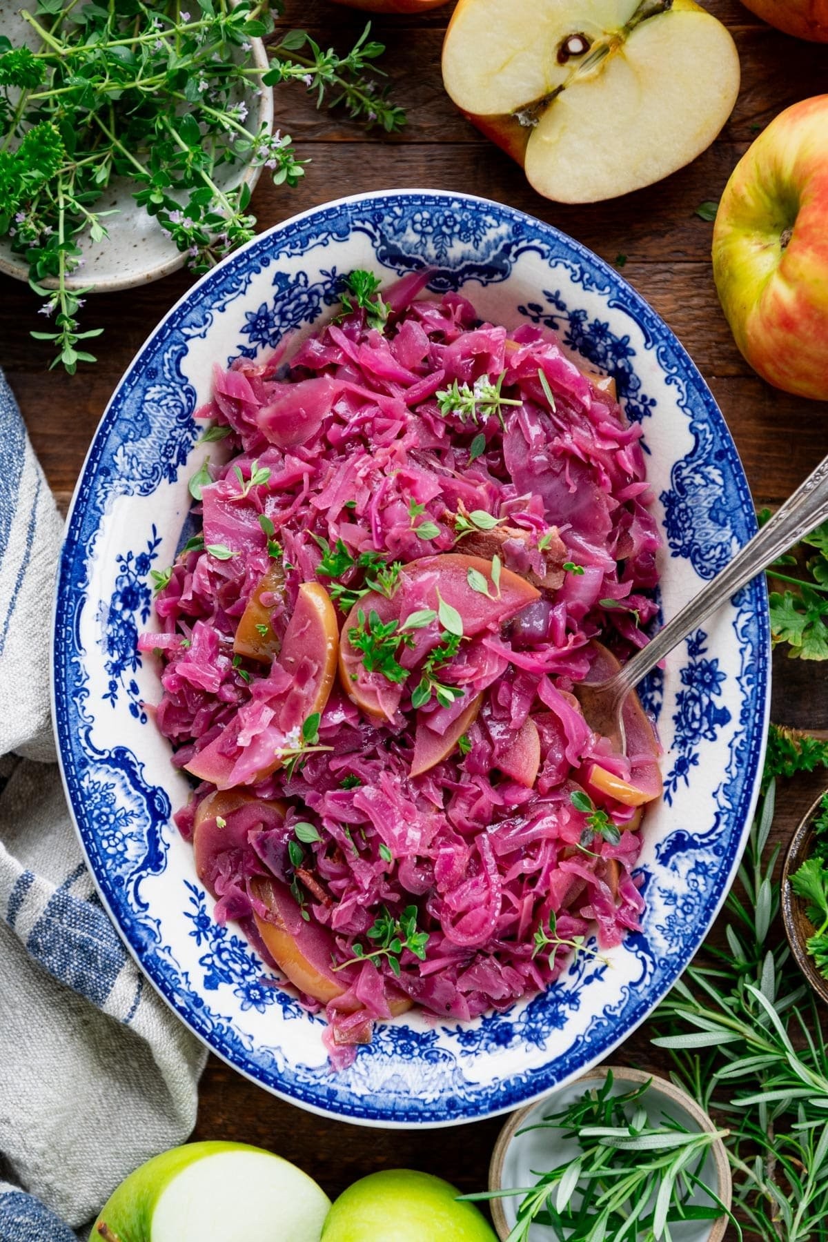 Delicious braised red cabbage with apples and onions, garnished with fresh herbs in a rustic serving dish
