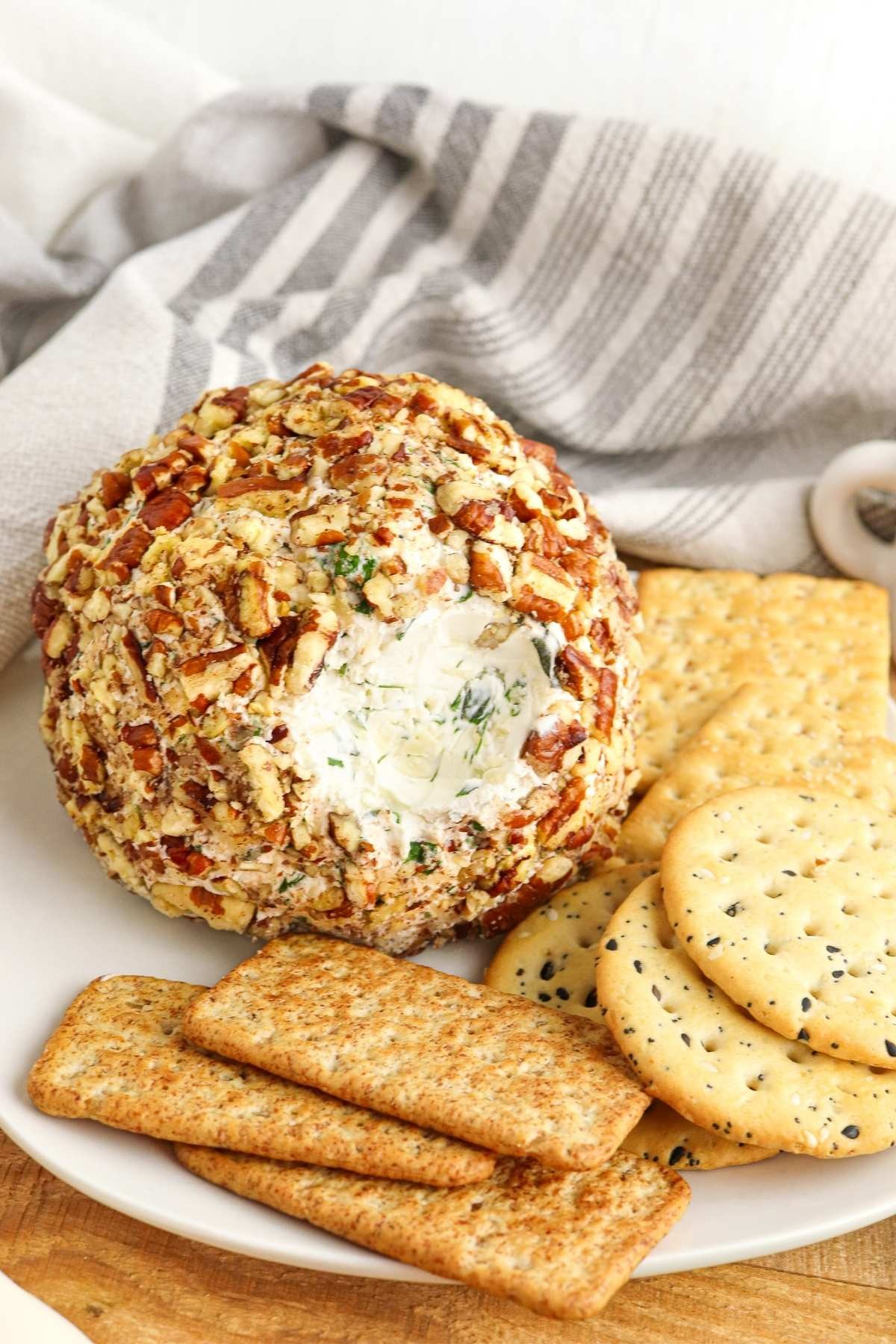beautifully presented herbed cheese ball with crackers and fresh herbs on a wooden board
