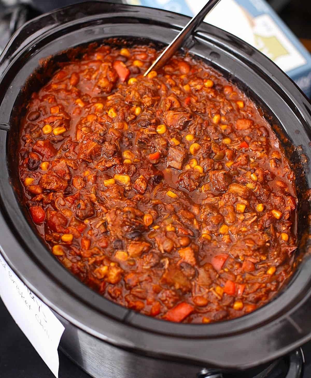 A hearty bowl of BBQ chili with smoke-filled background