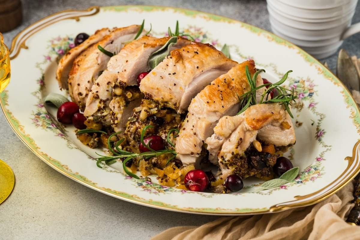 golden brown herb crusted turkey breast with carving knife and juicy slices on a platter