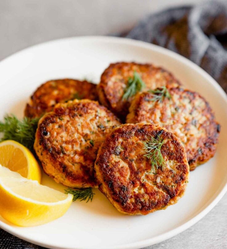 Delicious, golden-brown salmon patties on a plate, garnished with fresh dill