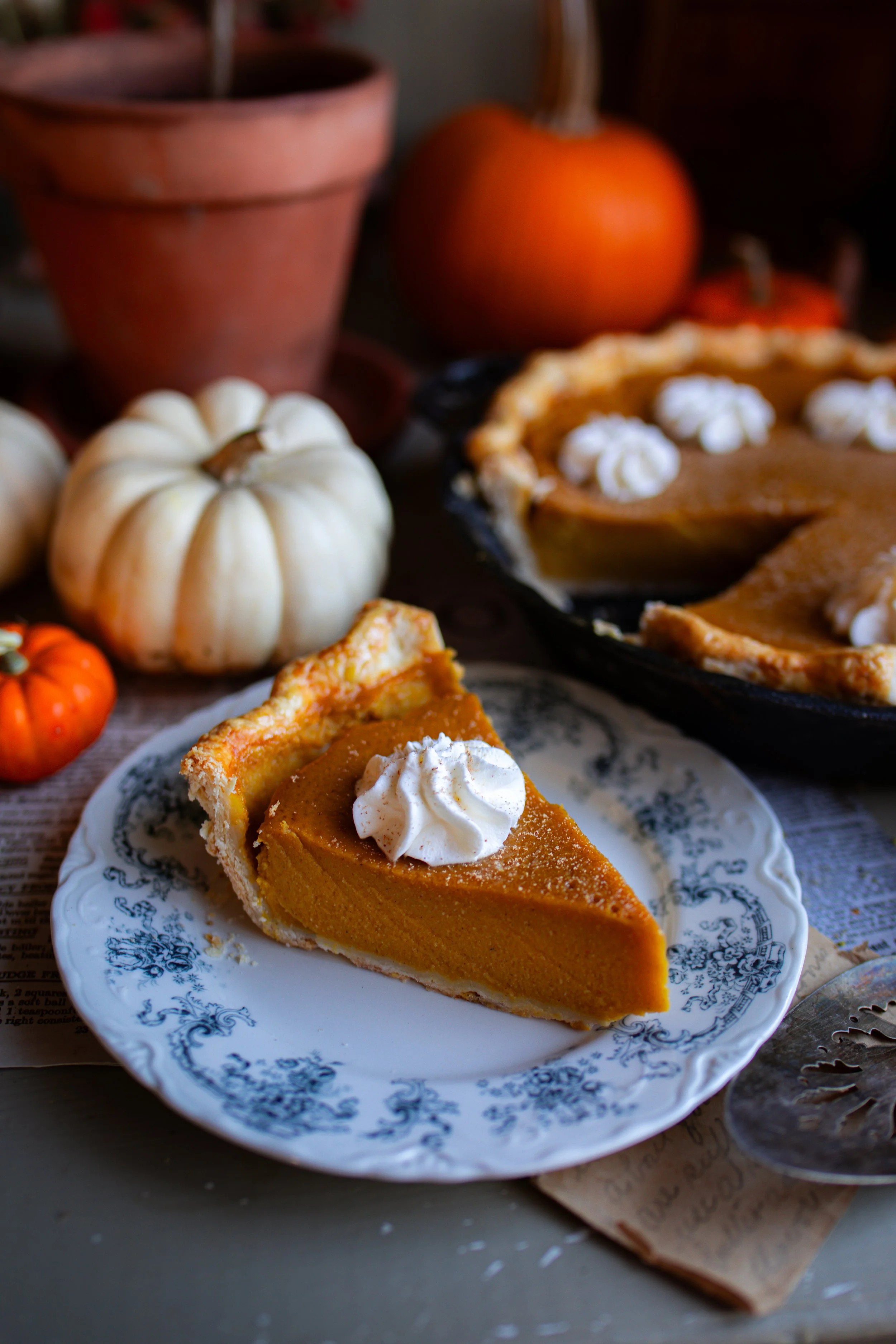 classic pumpkin pie with whipped cream and fall decorations, cozy kitchen setting