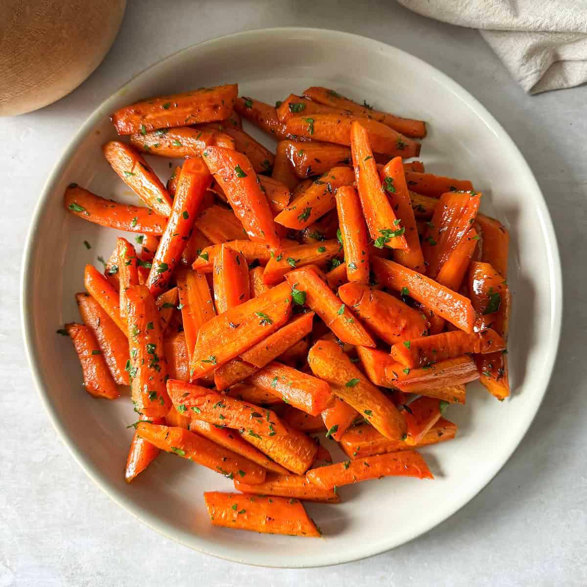 Overhead shot of a serving dish filled with roasted carrots, garnished with fresh herbs