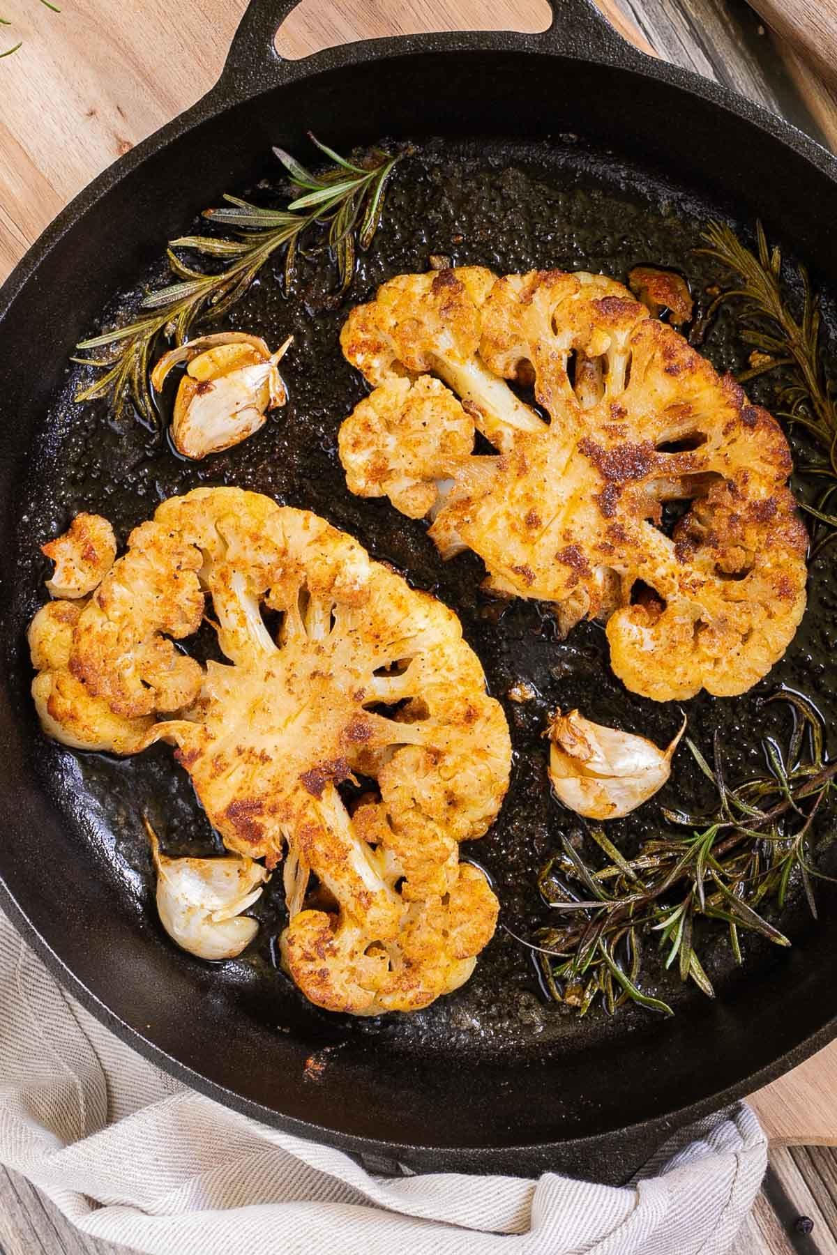 Cauliflower steak sizzling in a pan
