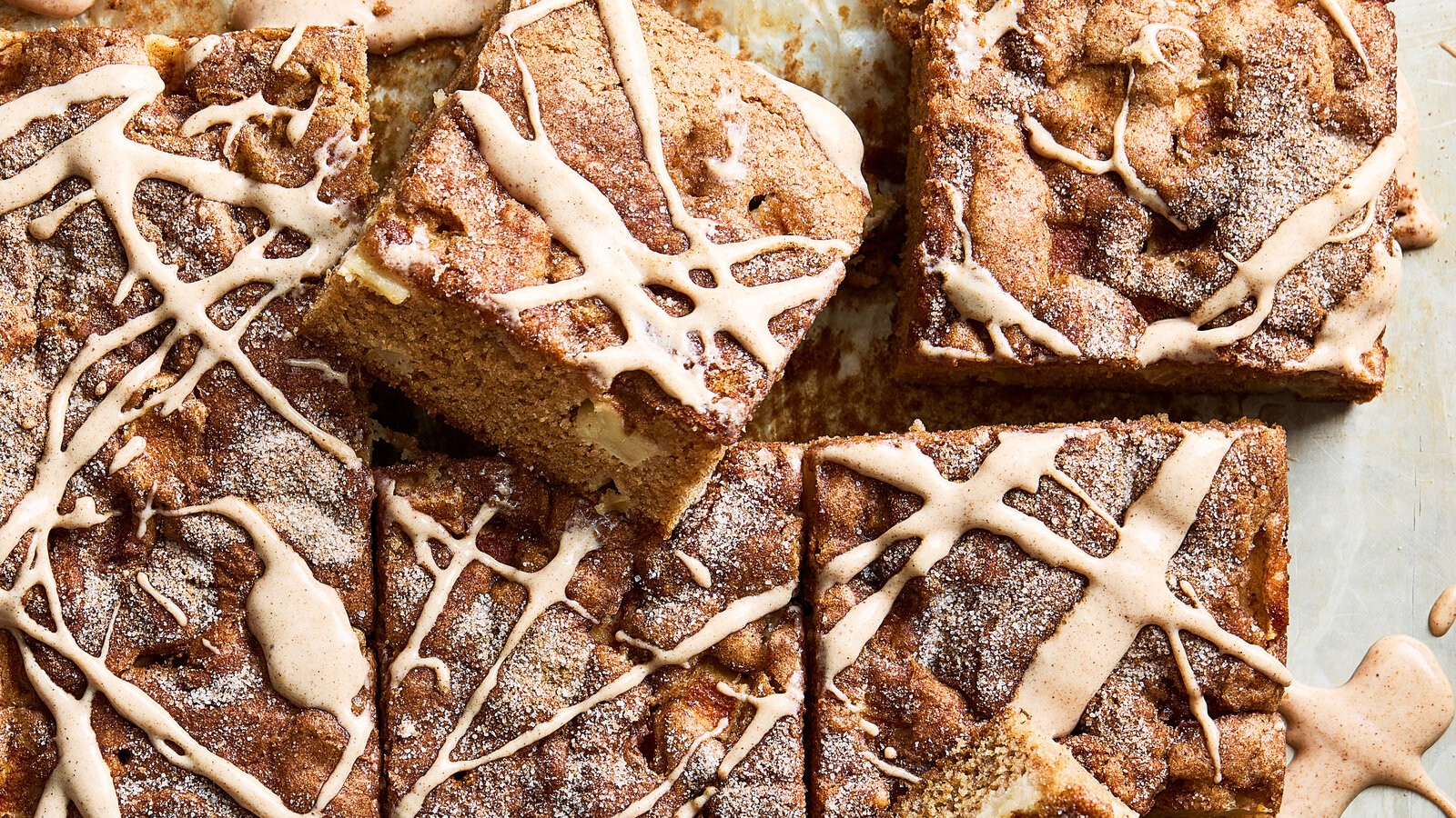 a warm cinnamon apple cake with a dusting of powdered sugar, surrounded by fall foliage