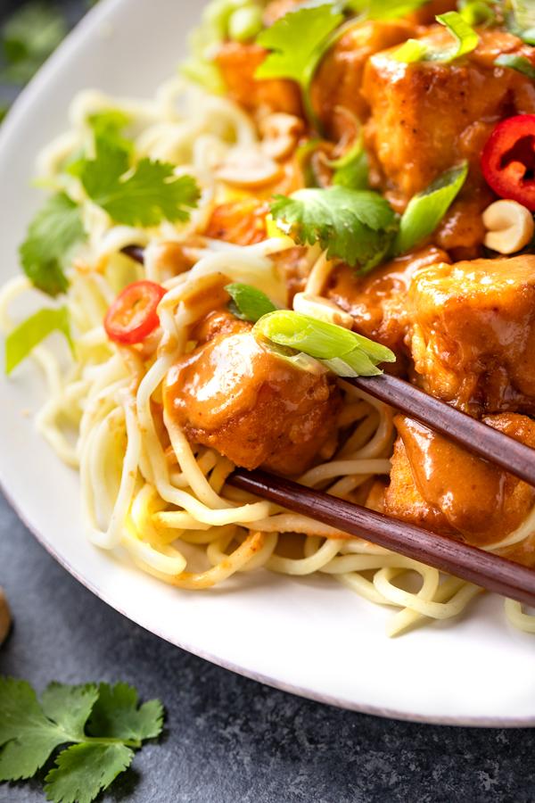 close up of spicy peanut sauce being drizzled on tofu