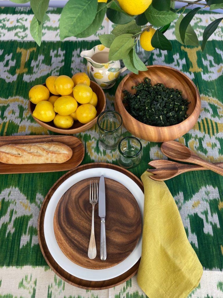 A rustic wooden table set with two plates of Kale & Quinoa Smørrebrød, garnished with sesame seeds and lemon wedges