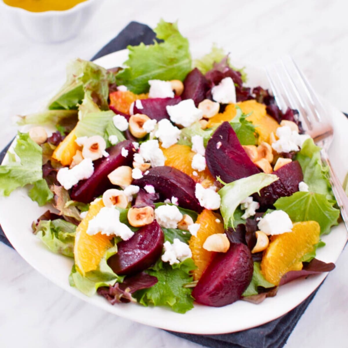 Colorful roasted beet salad with orange segments and a light citrus vinaigrette on a rustic wooden table, natural light