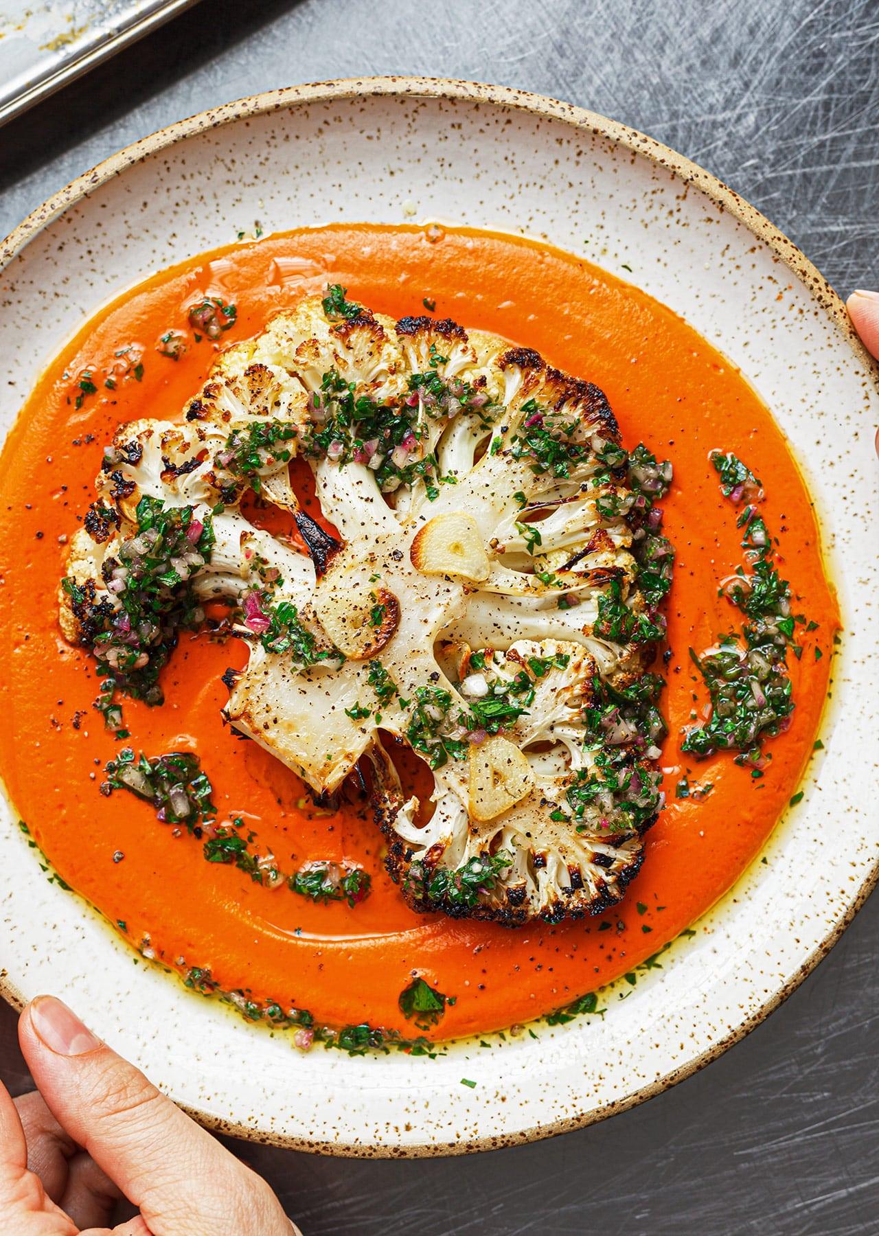 Close-up of a single cauliflower steak generously drizzled with romesco sauce